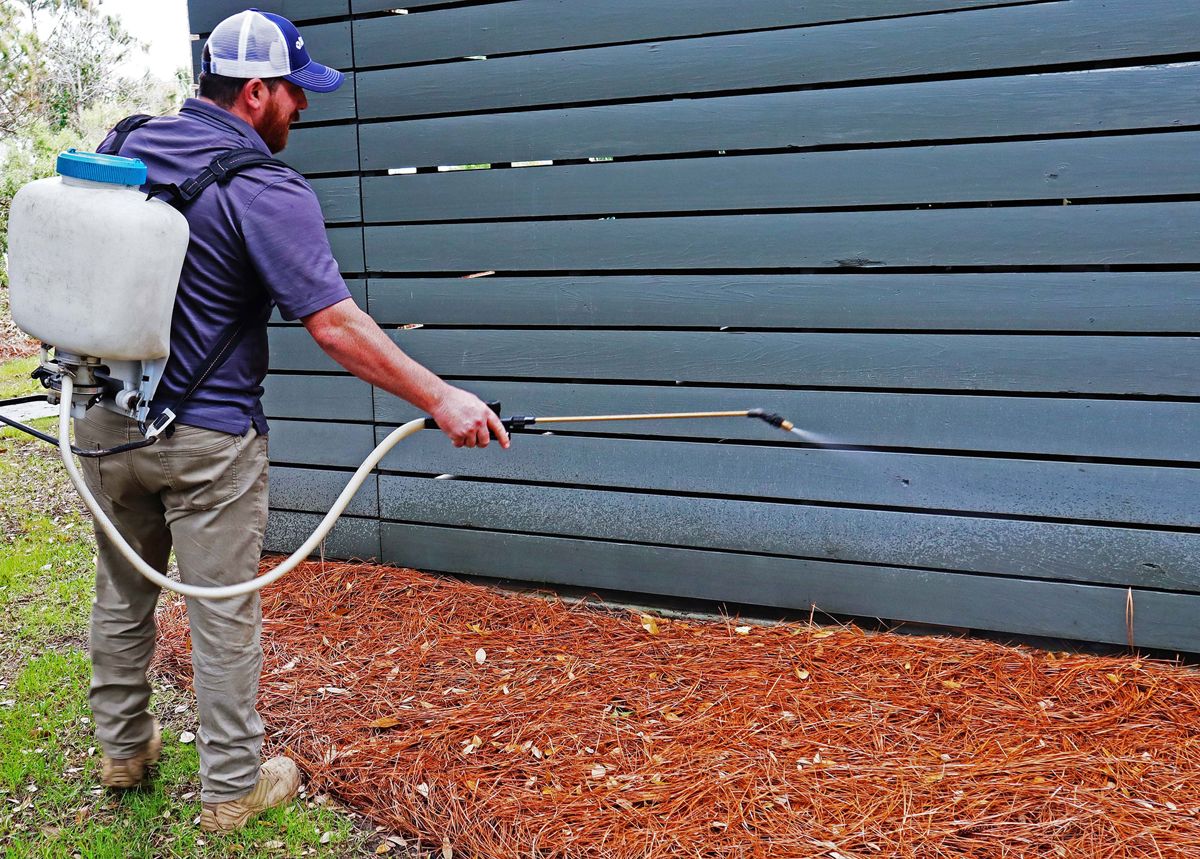 Pest control technician spraying a home exterior