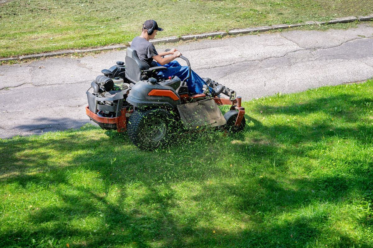 Landscaper mowing grass on a zero-turn mower