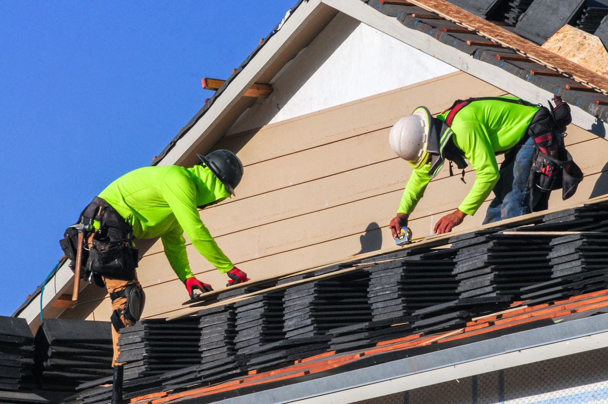 Roofing crew laying shingles on a pitched roof